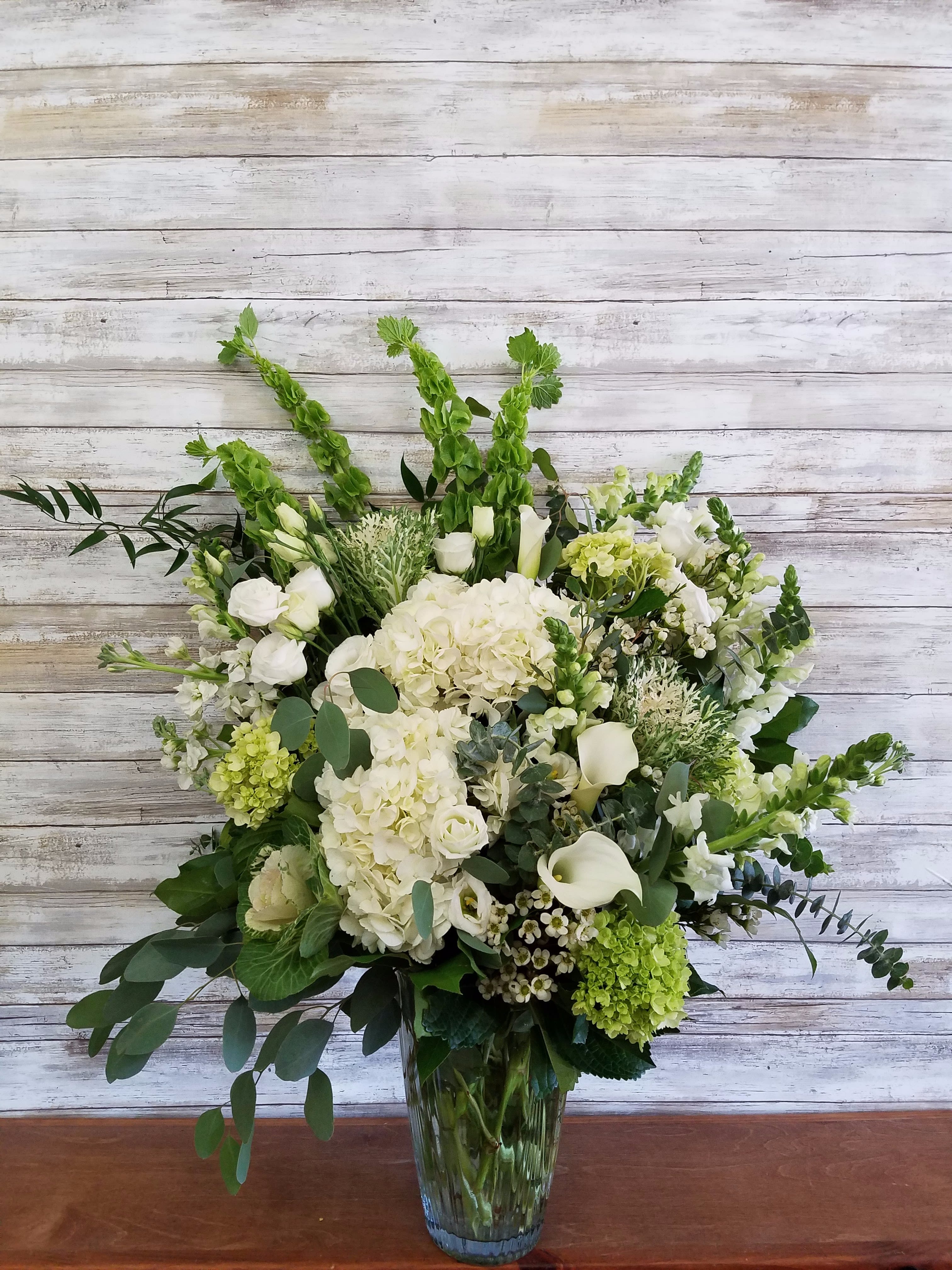 Peaceful Tribute Peaceful Tribute - A dreamy bouquet of white sympathy flowers is a comforting reminder of your love. The lush arrangement of soft colors is delivered in a majestic, tall glass vase. Hydrangea, Calla Lilies, Mini Green Hydrangea, Bells of Ireland, Stock, Kale, Snapdragons, Waxflower and various greens including Eucalyptus. Approx 30" Tall