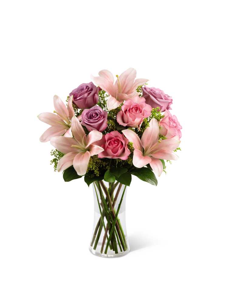 The FTD Farewell Too Soon Bouquet - The FTD Farewell Too Soon Bouquet is a blushingly beautiful way to convey your deepest sympathies for their loss. Pink and lavender roses are offset by pink Asiatic lilies, solidago and lush greens, perfectly arranged in a clear glass vase, to offer warmth and comfort to those facing the loss of their loved one.
