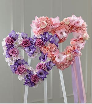 The FTD® Hearts Eternal™ Easel - Pay tribute to a love that not even death can diminish. This creative and eloquent statement of everlasting romance is expressed by a pair of floral hearts, beautifully entwined. Handcrafted by a local FTD artisan florist, this poetic masterpiece of sympathy is designed to be displayed on a wooden easel at a wake, a funeral service, or a graveside burial service. It includes pink carnations, roses and gladiolus, lavender cushion pompons and roses and purple gladiolus ... a very personal and loving tribute to the memory of one who was extravagantly loved.  Your purchase includes a complimentary personalized gift message.