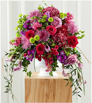 The FTD® Our Love Eternal™ Arrangement The FTD® Our Love Eternal™ Arrangement - When you are looking for an outstanding, yet appropriate expression of sympathy at a wake or funeral, this colorful mixed flower bouquet makes an exquisite choice. Handcrafted by a local FTD artisan florist this vibrant purple and pink arrangement combines mini calla lilies, spider chrysanthemums, roses, stock, bupleurum, pompons and hydrangeas with a cascade of lush greenery that creates the illusion of "weeping". It is set in a generously scaled plastic urn that has the look of white ceramic and makes an impressive and memorable way to deliver your condolences and manifest your sadness at a wake, funeral service or at the graveside. Your purchase includes a complimentary personalized gift message.
