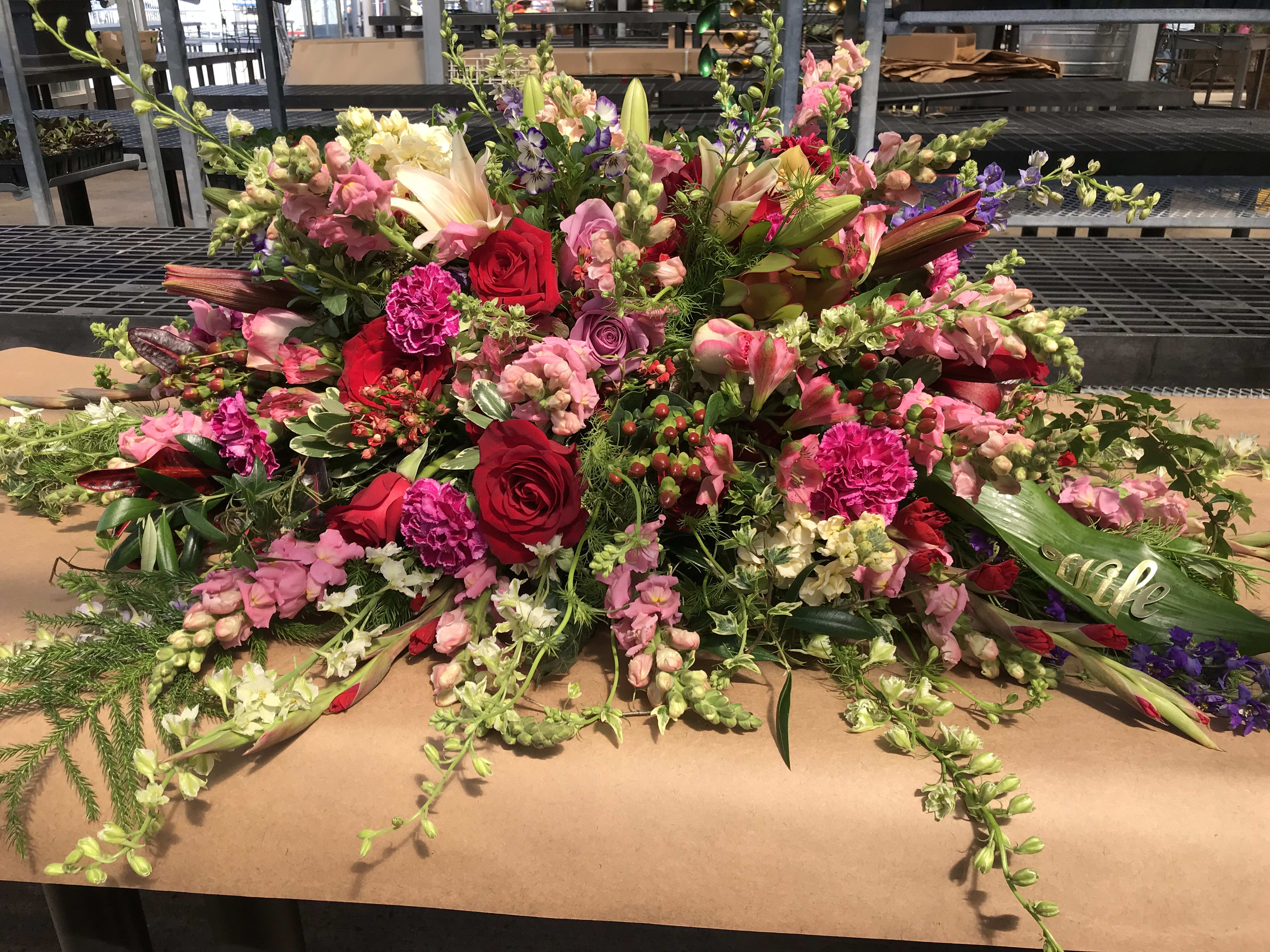 Casket Spray - Our artisan handmade arrangement's overall theme is different shades of pink. The actual bouquet or arrangement may not precisely match the photo,but its temperament will. The freshest, artisan flowers available are used to create an exquisite arrangement especially for you. We also use a variety of unusual greenery for an example eucalyptus, salal (lemon leaf), pittisporum. Occasionally, substitutions of flowers or containers happen due to weather, seasonality and market conditions which may affect availability. If this is the case with the gift you've selected,we will ensure that the style, theme and color scheme of your arrangement is preserved and will only substitute items of equal or higher value.