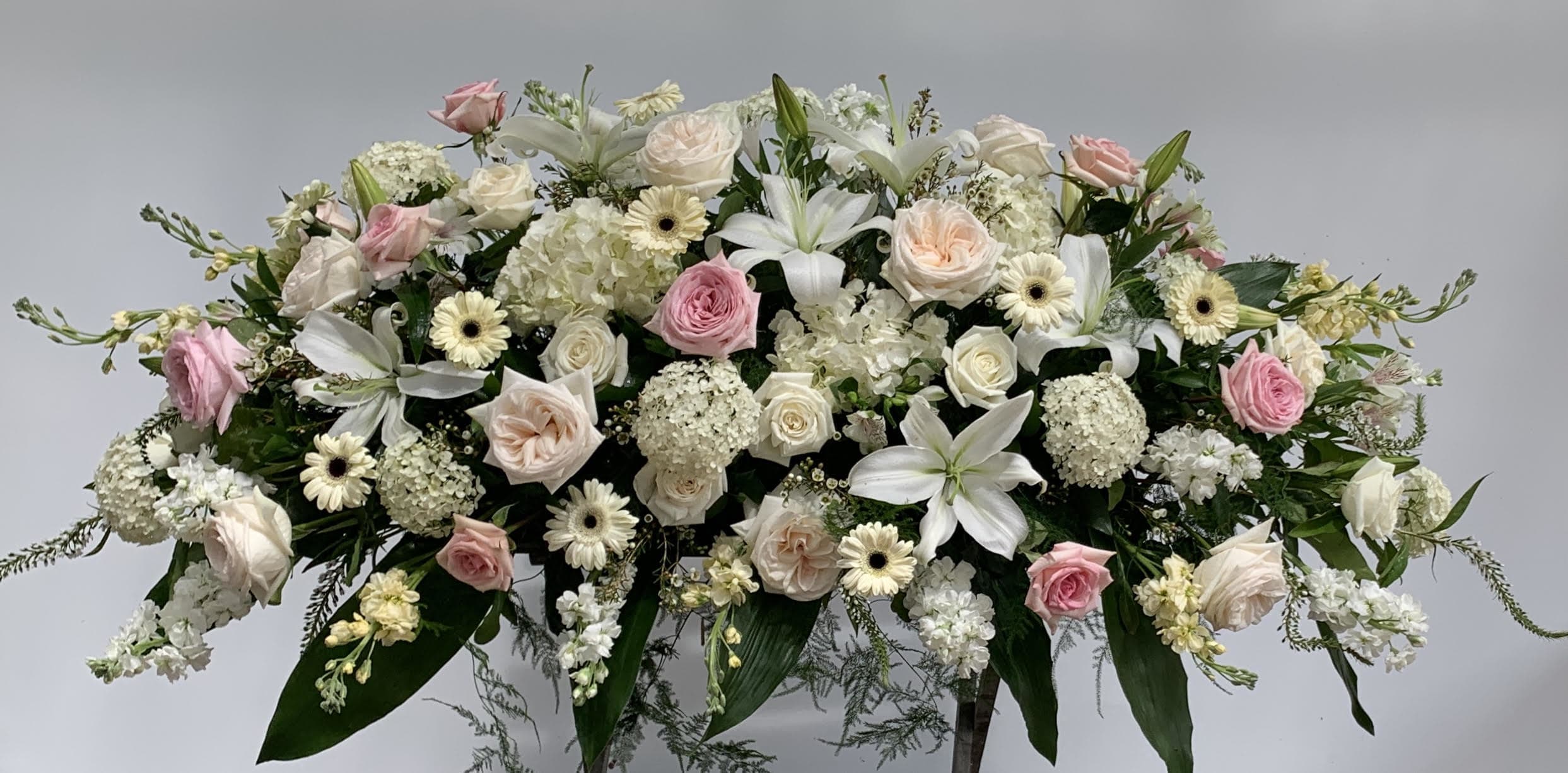 Traditional Casket Spray Traditional Casket Spray - A mixture of pink and white garden flowers for a casket spray. This piece is approximately four feet long. Please call store to place order so that we may verify service day and time. *UNAVAILABLE FOR SAME DAY DELIVERY.*