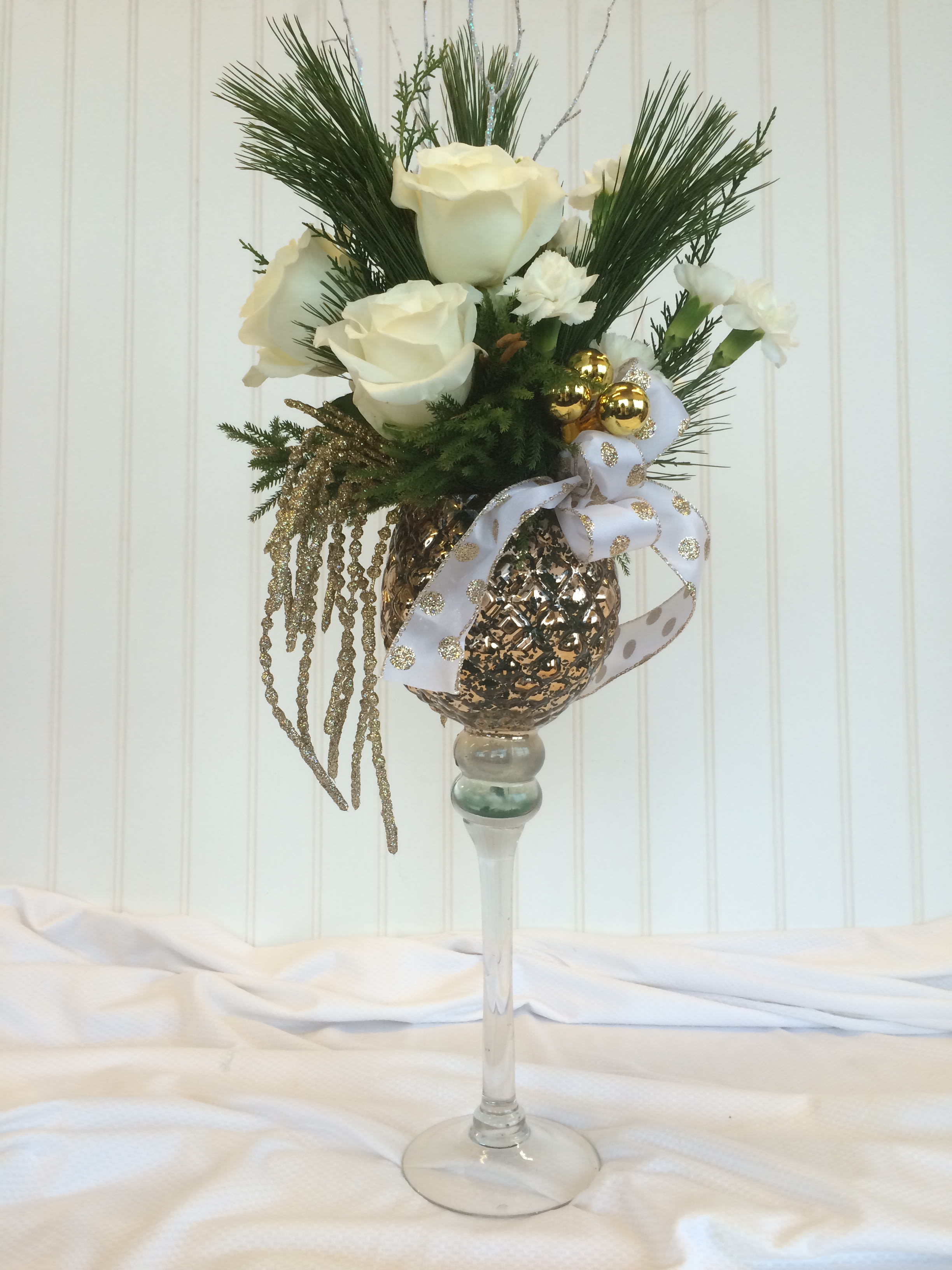 Golden Glory - A classy golden goblet designed with all white flowers &amp; evergreens. Trimmings of gold bling &amp; ribbon to grace your table!
