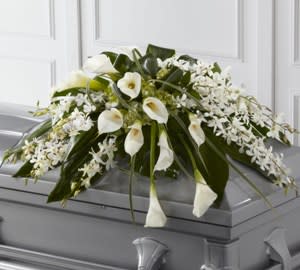 Angel Wings Casket Spray - Elegant in all white, calla lilies, dendrobium orchids, tropical leaves.  Script can be added to this piece. Due to current market conditions, substitutions will happen.