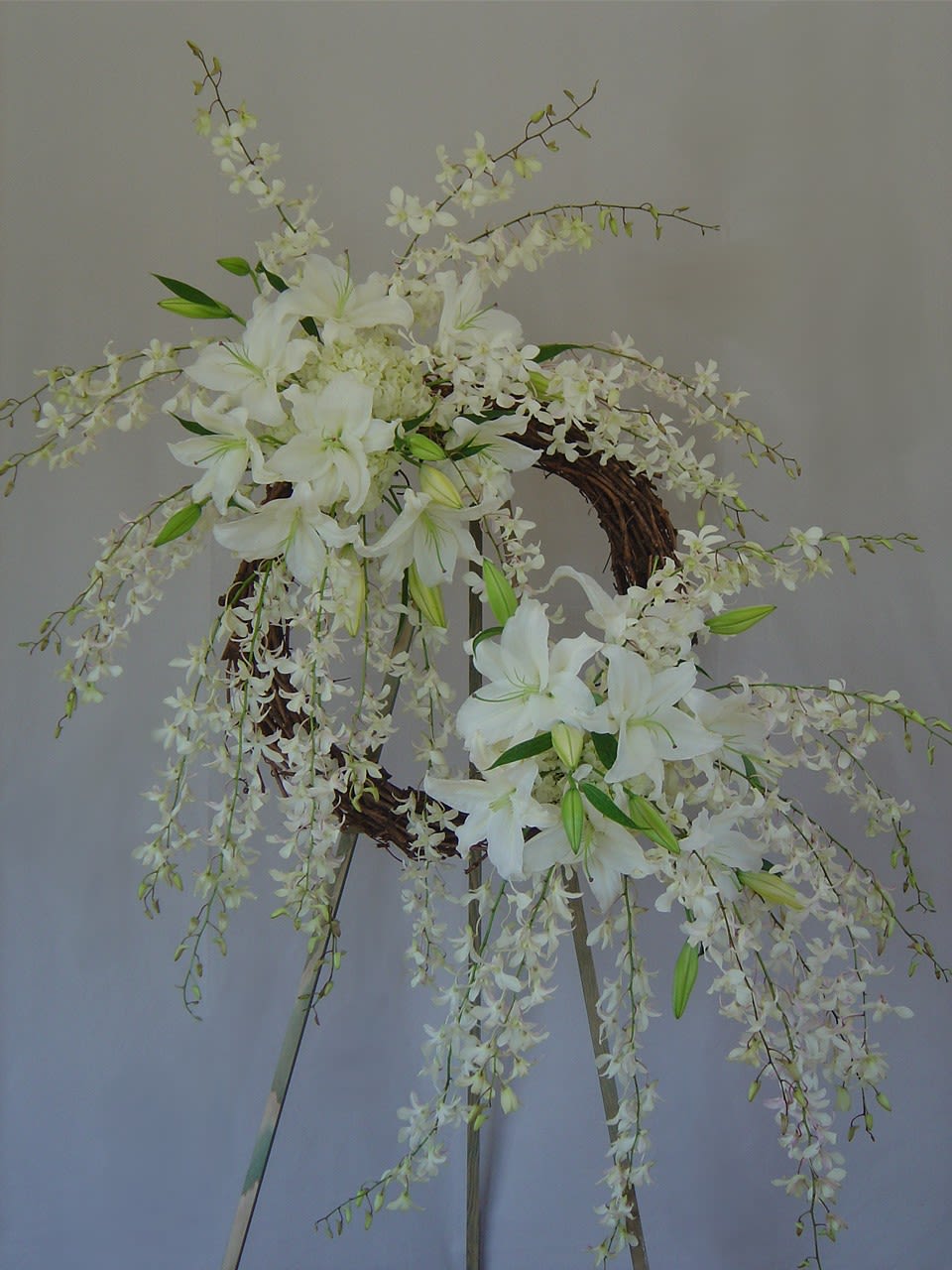 Eternal Bond Wreath Eternal Bond Wreath - Natural looking wreath with two clusters of flowers: hydrangeas, lilies, and Hawaiian dendrobium orchids (easel included).