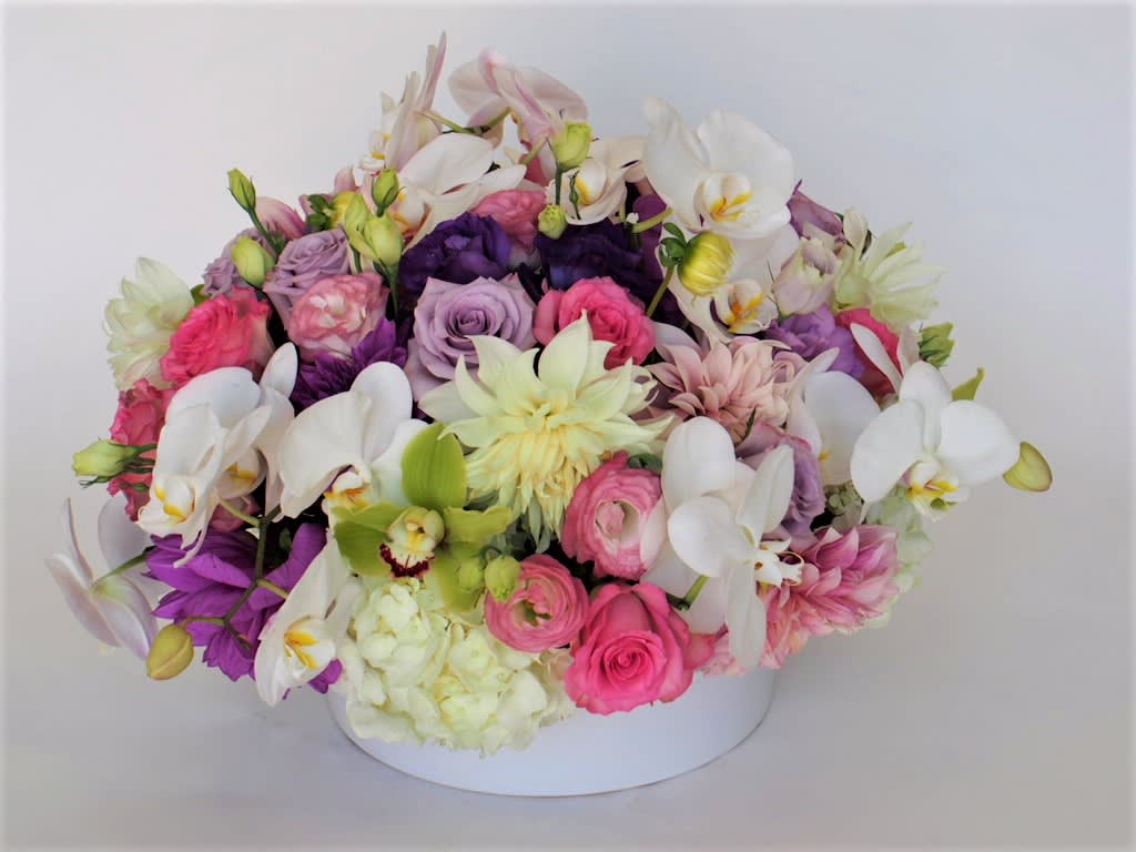 Paris Paris - A lush arrangement in ceramic container, pastel with a pop of a deep color like purple. Exact flowers and container might change due to season or avilability.