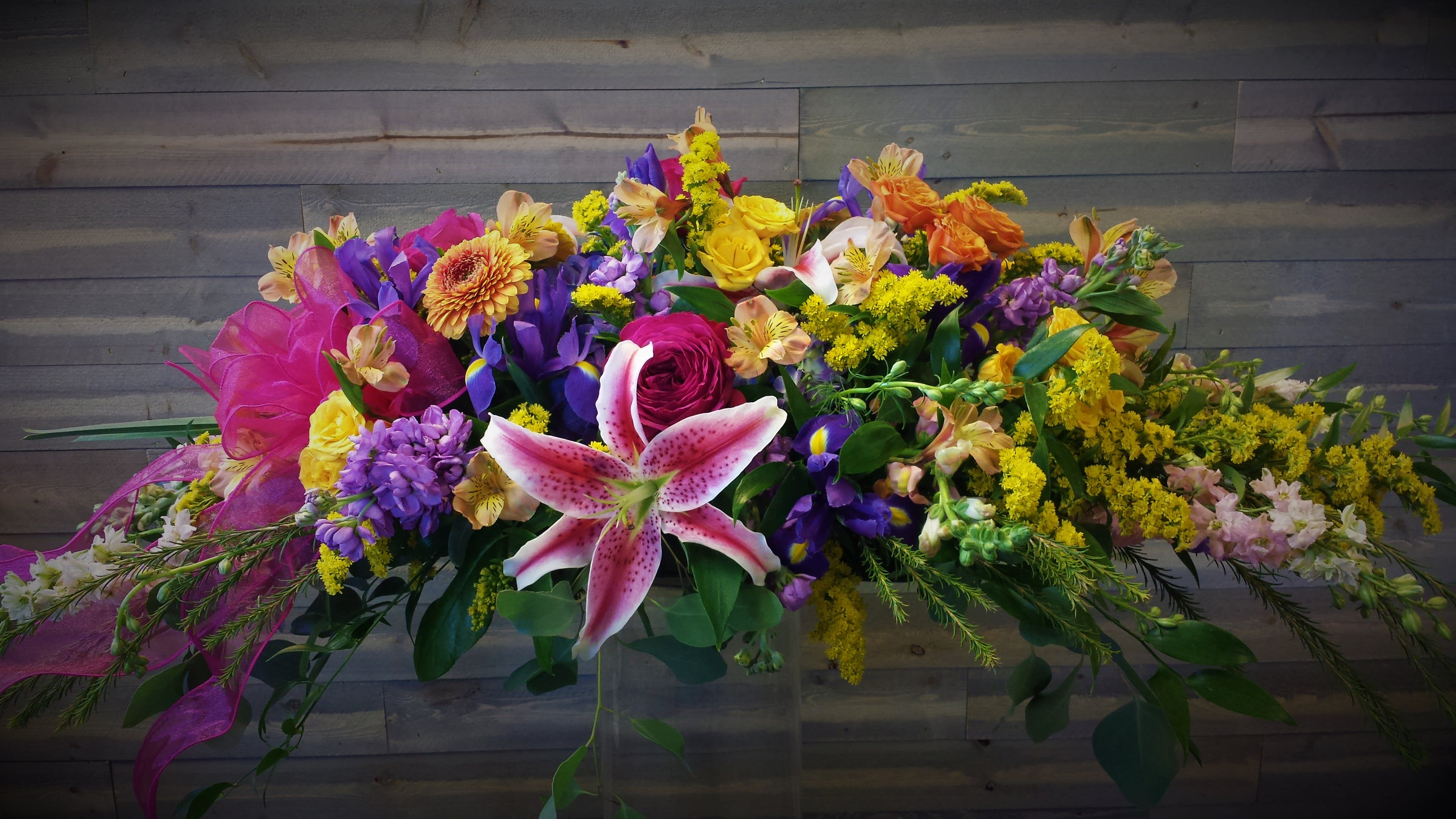 rainbow floral spray - a bountiful rainbow colored casket spray 
