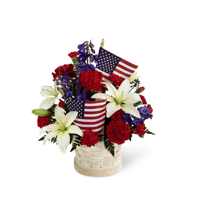 FTD American Glory Bouquet - The FTD American Glory Bouquet bursts with patriotic pride and  heartfelt beauty. Blue delphinium, bright red carnations and mini  carnations and brilliant white Asiatic lilies create a spectacular  display arranged amongst American Flags in a round whitewash basket,  creating a lovely way to celebrate this coming July 4th holiday. 18h x 12w 