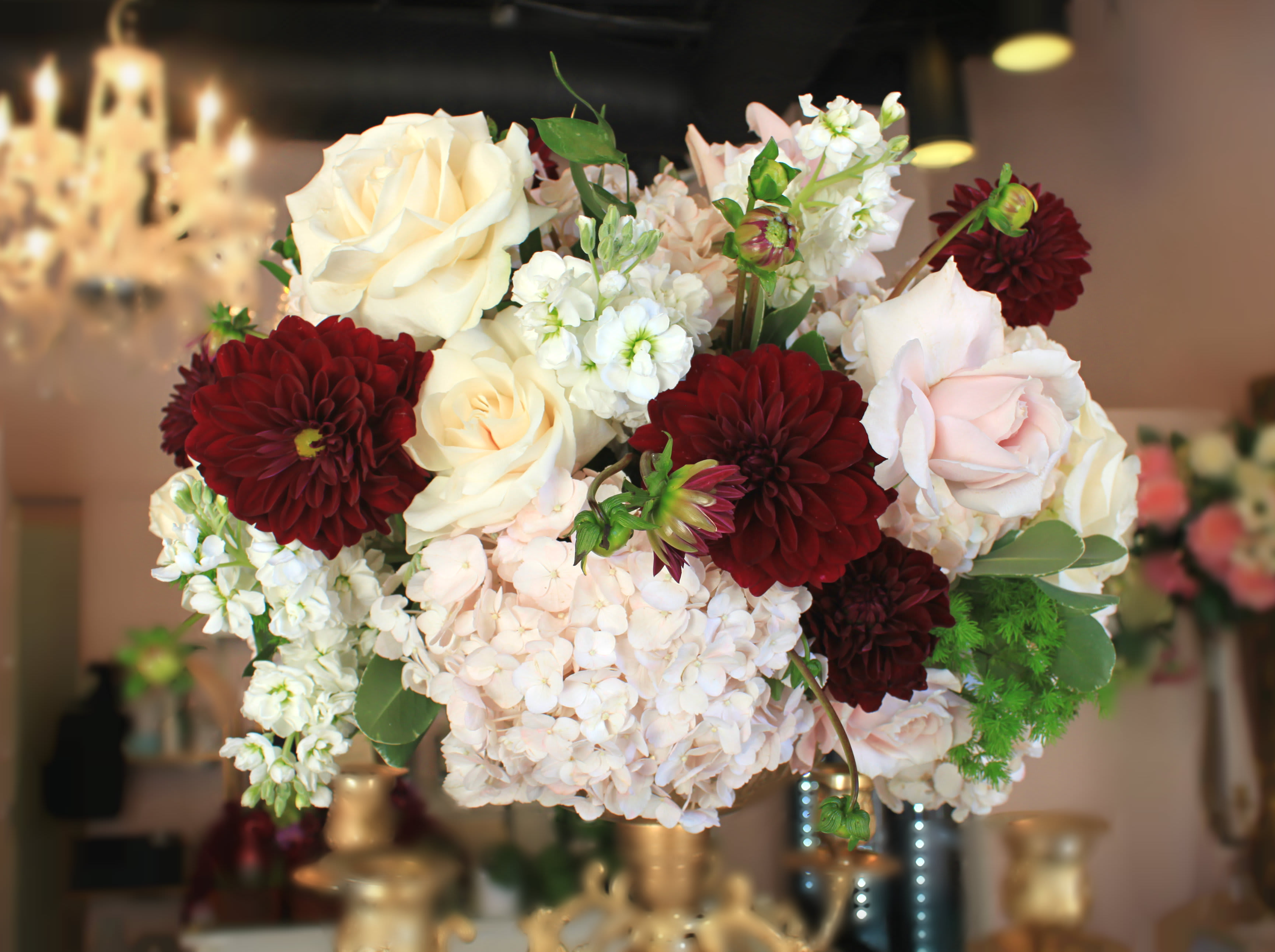 Miranda - A fun arrangement with a pop of marsala and greeneries on an unique glass vase.