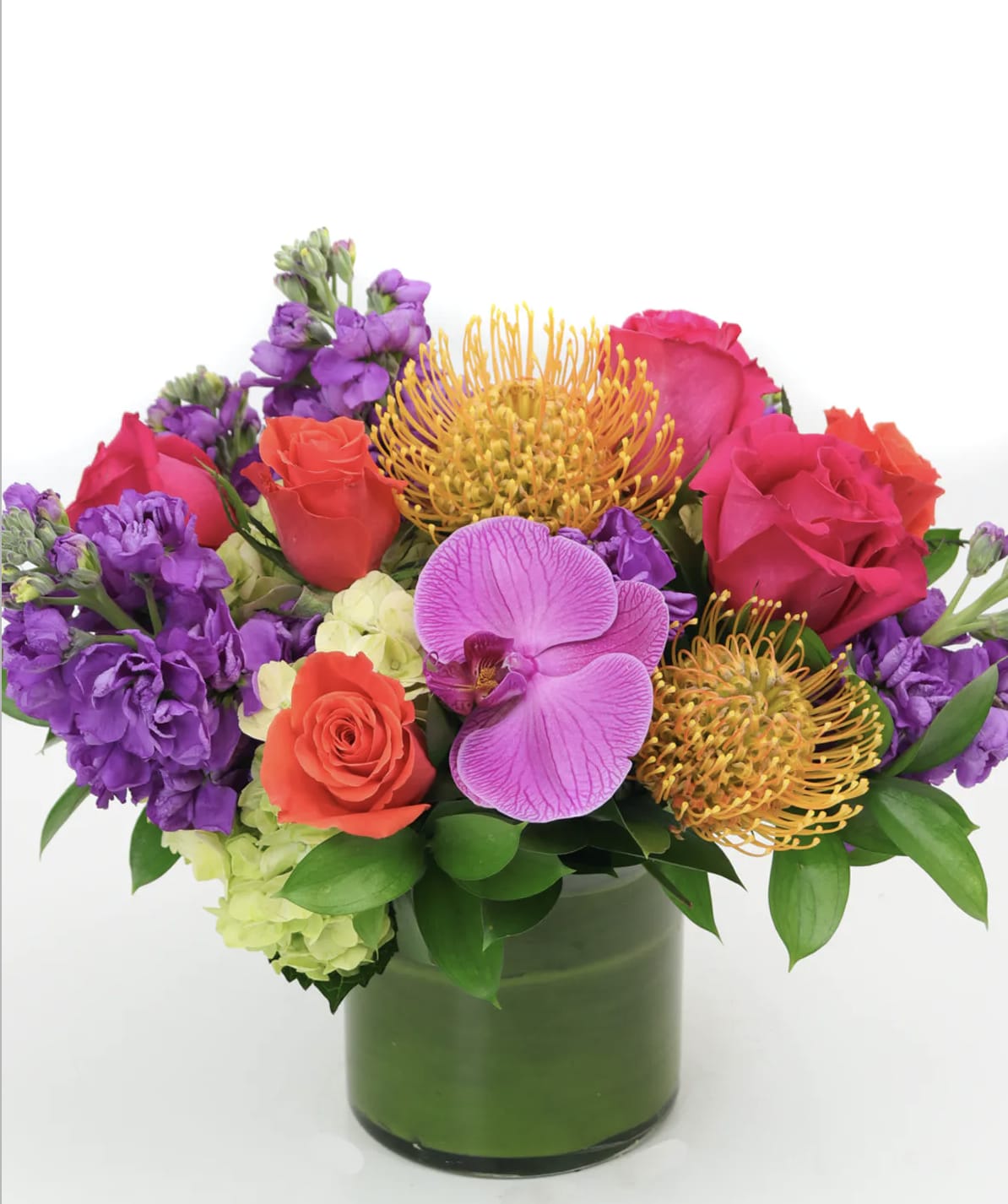Anaheim Dreams - Rekindle warm feelings with this sweet but sizzling array of hot pink roses, orange spray roses, orchids, protea and more in a tea leaf wrapped glass bowl. 