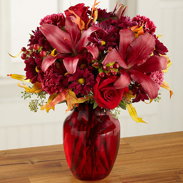 The FTD Autumn Treasures Bouquet The FTD Autumn Treasures Bouquet - Mirroring the hue of a great cabernet sipped on a cool autumn day this elegant flower bouquet is sure to capture their heart. Rich red roses burgundy daisies burgundy carnations and red Asiatic Lilies are accented with red hypericum berries seeded eucalyptus and glycerized oak leaf stems styled in a ruby glass vase. An impressive thank you birthday or Thanksgiving gift. GOOD bouquet includes 13 stems. Approx. 13"H x 11"W. BETTER bouquet includes 17 stems. Approx. 13"H x 12"W. BEST bouquet includes 20 stems. Approx. 15"H x 13"W.