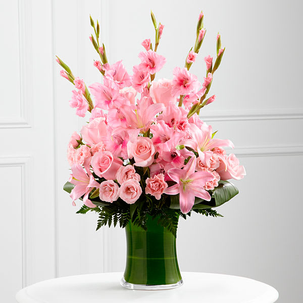 The FTD Lovely Tribute Bouquet The FTD Lovely Tribute Bouquet - The FTD® Lovely Tribute™ Bouquet is a warm and blushing display of peace and beauty set to honor the deceased and bring comfort to family and friends. Pink gladiolus pale pink roses bi-color pink roses pink Asiatic lilies and an assortment of lush greens create a sophisticated arrangement seated in a clear glass gathering vase symbolizing your heartfelt love and sympathy.