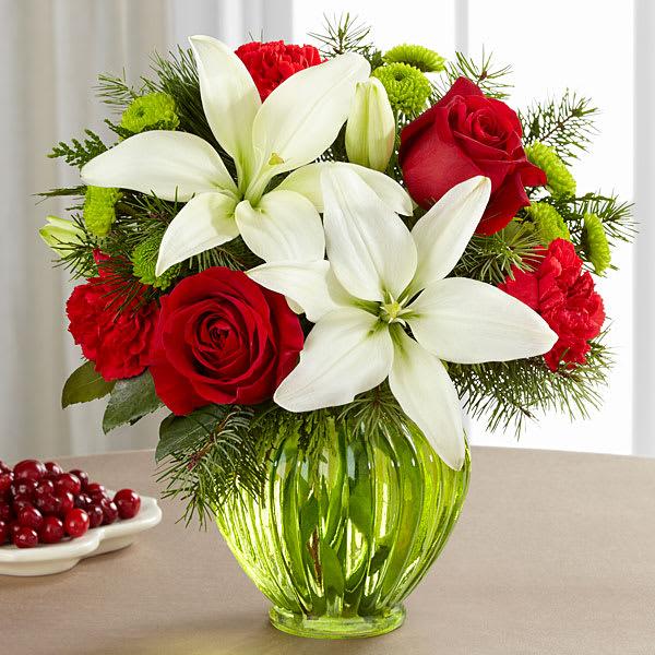 The FTD Winter Elegance Bouquet - The FTD® Winter Elegance™ Bouquet blooms with holiday charm and Christmas joy to extend your warmest season's greetings to friends family and co-workers. Rich red roses and bright red carnations are brought together with green button poms white Asiatic lilies and an assortment of lush holiday greens to create an incredible fresh flower arrangement. Presented in a stylish green ginger vase this holiday flower bouquet is set to make their yuletide season both merry and bright.