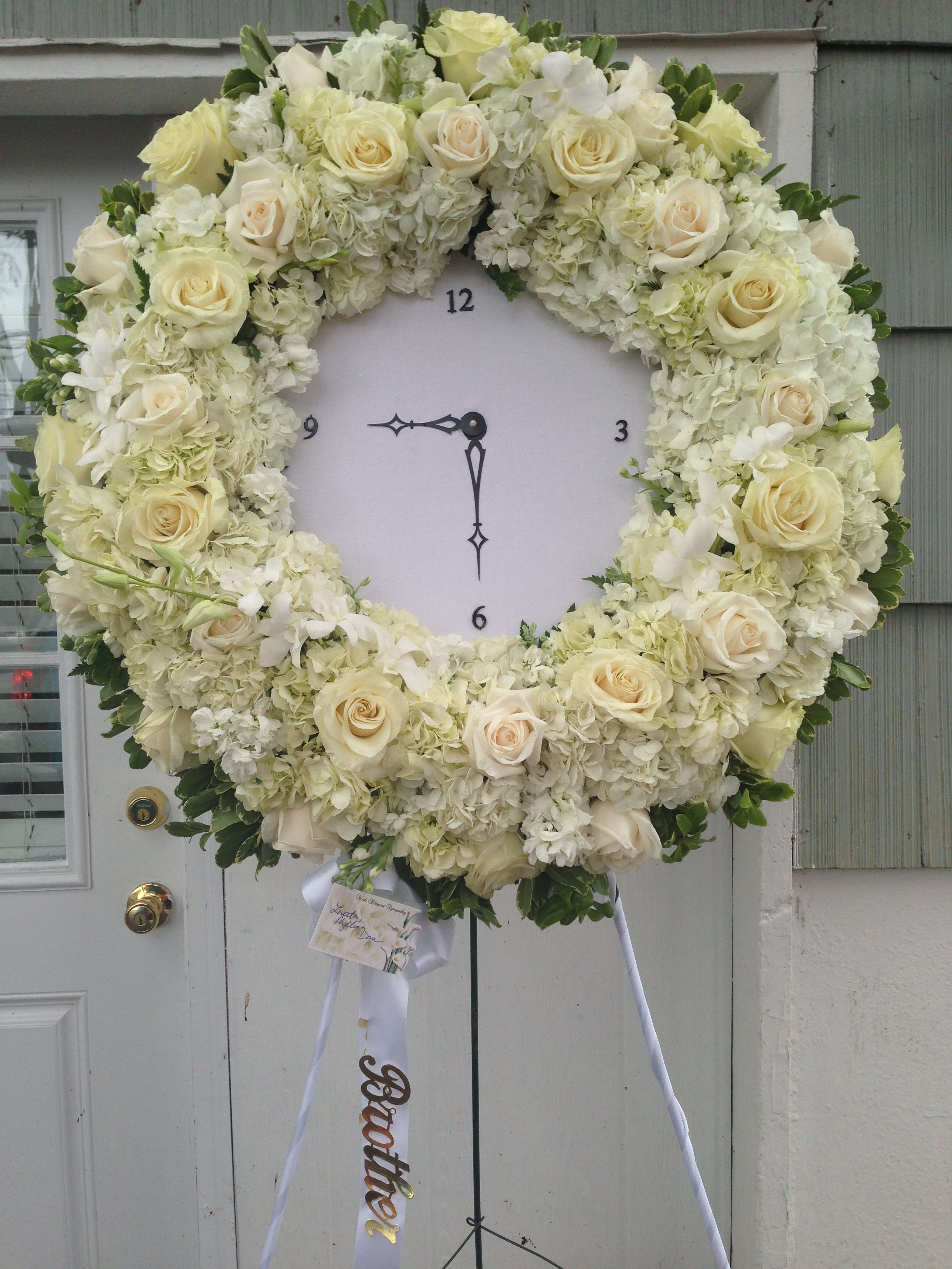 Large Wreath Clock - This sympathy piece represents the time your loved one passed. The clock is surrounded by all white flowers. Hydrangea, roses and orchids.  * Can be made in any choice color