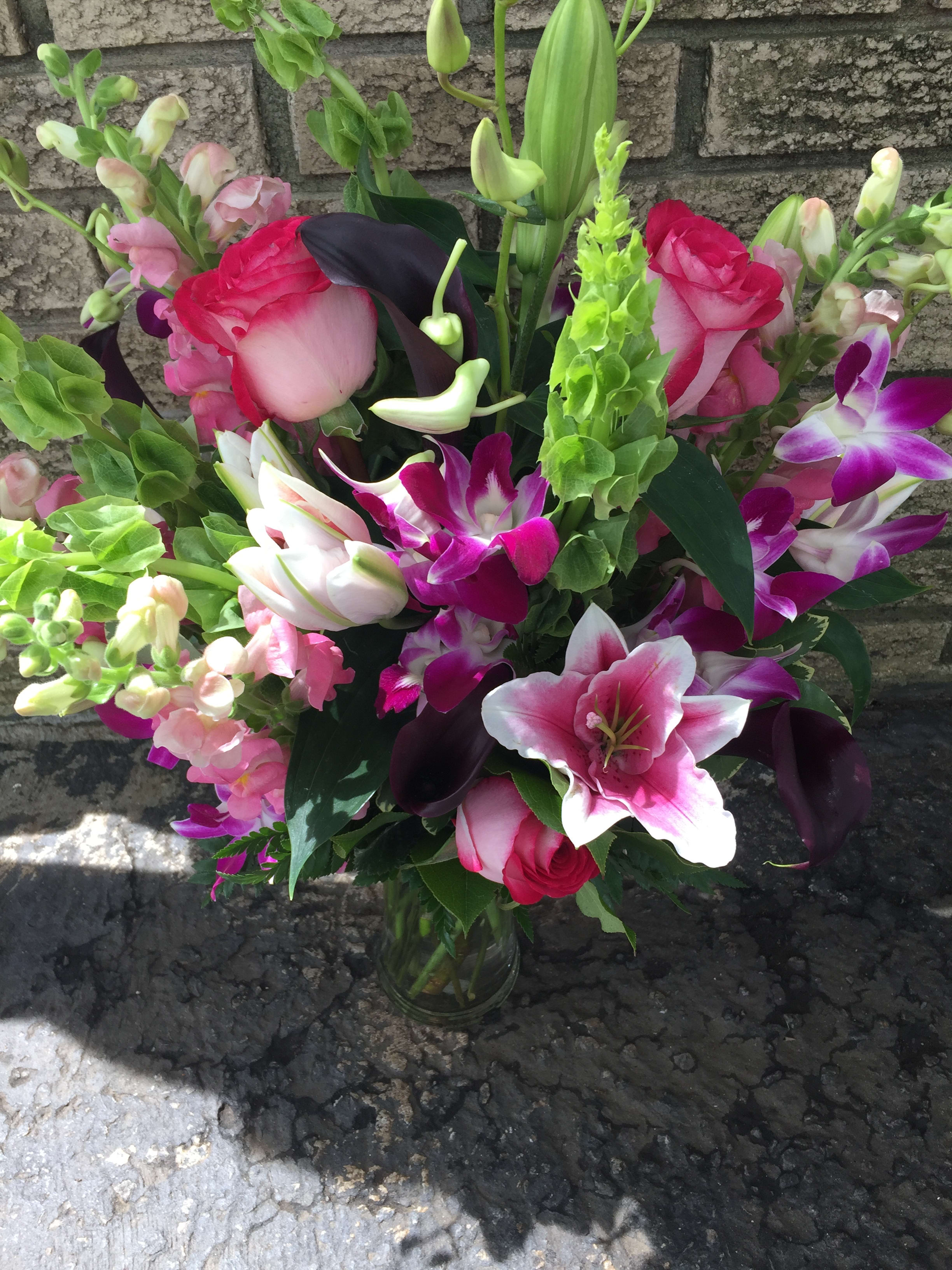 Pinks &amp; Things  - Tall vase bursting with purples and pinks. Sorbonne Lilly, purple orchids, eggplant calla Lilly, hot pink roses, bells of Ireland and pink snap dragon. 