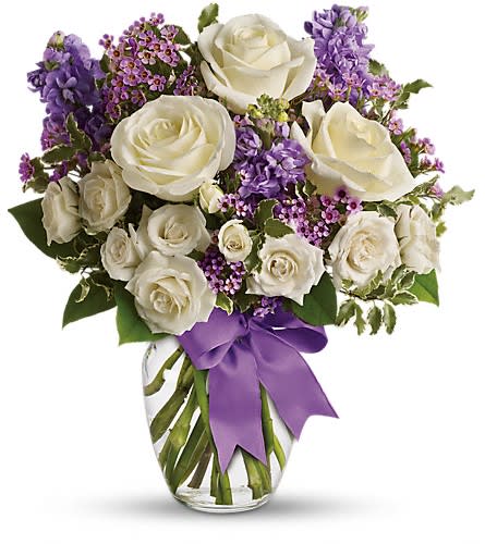 Teleflora's Enchanted Cottage - This magical bouquet will be at home in a cottage a condo a studio or an estate. It's so pretty it will be appreciated by all those lucky enough to receive it. Enchant someone today! White roses and spray roses lavender stock and waxflower all perfectly arranged in a clear glass vase that's wrapped with purple ribbon.Approximately 14 1/2&quot; W x 16 1/2&quot; H Orientation: One-Sided As Shown : T50-1ADeluxe : T50-1BPremium : T50-1C