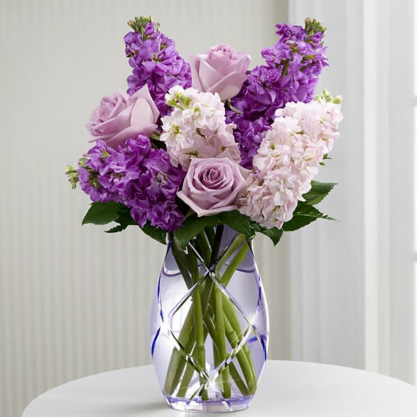 The FTD Sweet Devotion Bouquet by Better Homes and Gardens - Lavender roses are paired with textured columns of lavender and pink gilly flowers and accented with vibrant, lush greens in a heavy, lilac-hued glass vase cut all around with a sparkling lattice.