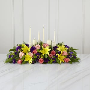 The FTD Forever Arrangement - This inspirational altar piece handcrafted by a local FTD artisan florists makes an inspired contribution to a funeral service – one that truly shows how much you care. Handcrafted by a local FTD artisan florist of peach and coral roses, purple lisianthus and asters, yellow Asiatic lilies and lush green accents in a long, low arrangement, it makes a natural setting for a variety of candles (included). As an accompaniment to a funeral, it’s an excellent choice for most services both elaborate and simple.