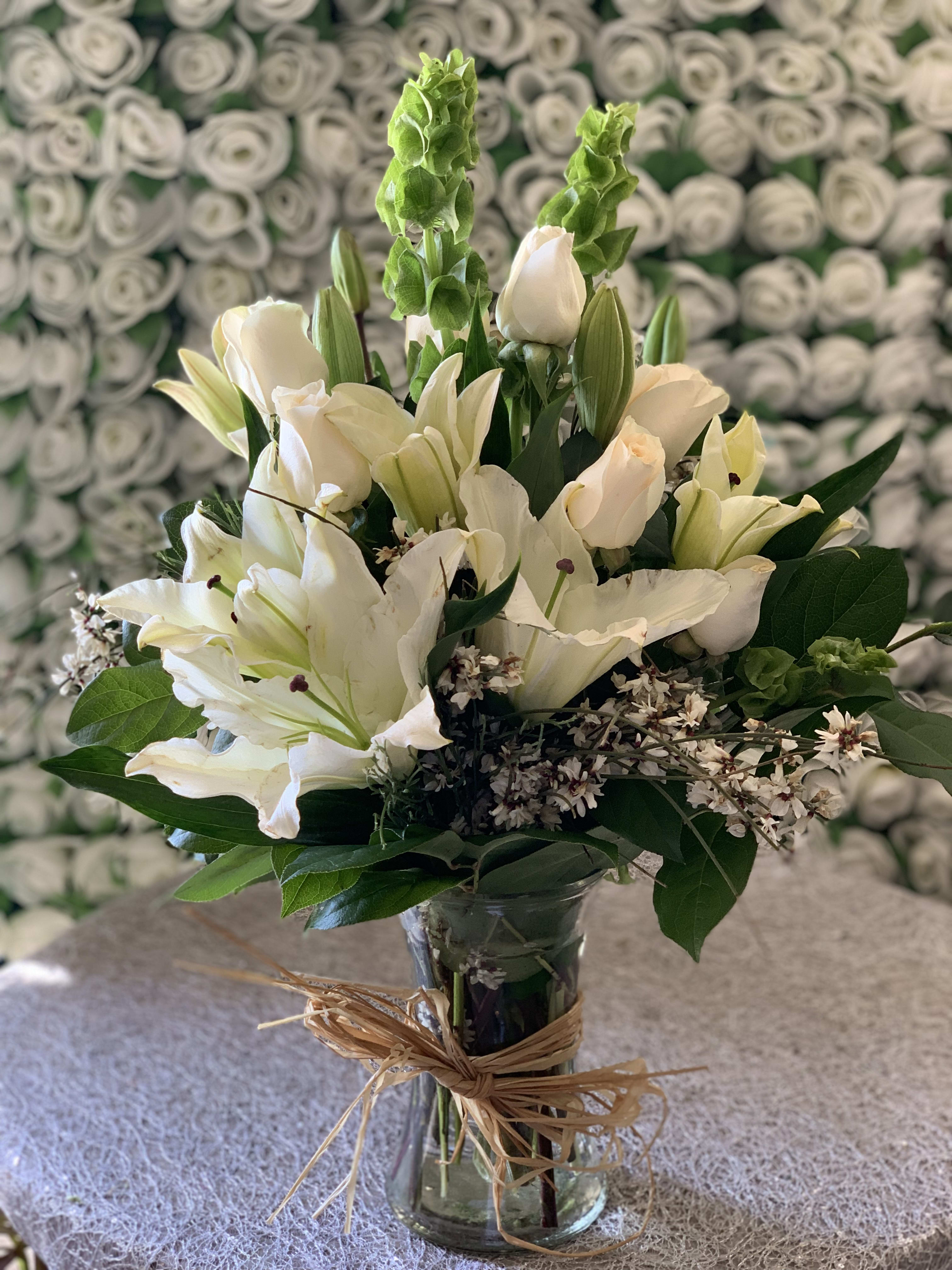 Eternal Love Bouquet - White lilies and roses infused with bells of ireland in a gathering vase. Tied with raffia ribbon