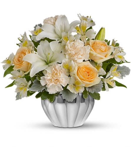 Teleflora's Kiss Me Softly Teleflora's Kiss Me Softly - If you're in the market for a beautiful bargain this fabulous floral gift is for you. It features lush peach roses white lilies and other favorites in a gleaming silver Jardiniere vase. So gorgeous so reasonable so easy to send. The stylish bouquet includes peach roses white asiatic lilies white alstroemeria and white carnations accented with assorted greenery.Delivered in a silver high-quality ribbed vase with a metallized finish.Approximately 14" W x 12" H Orientation: All-Around As Shown : TEV04-2ADeluxe : TEV04-2BPremium : TEV04-2C