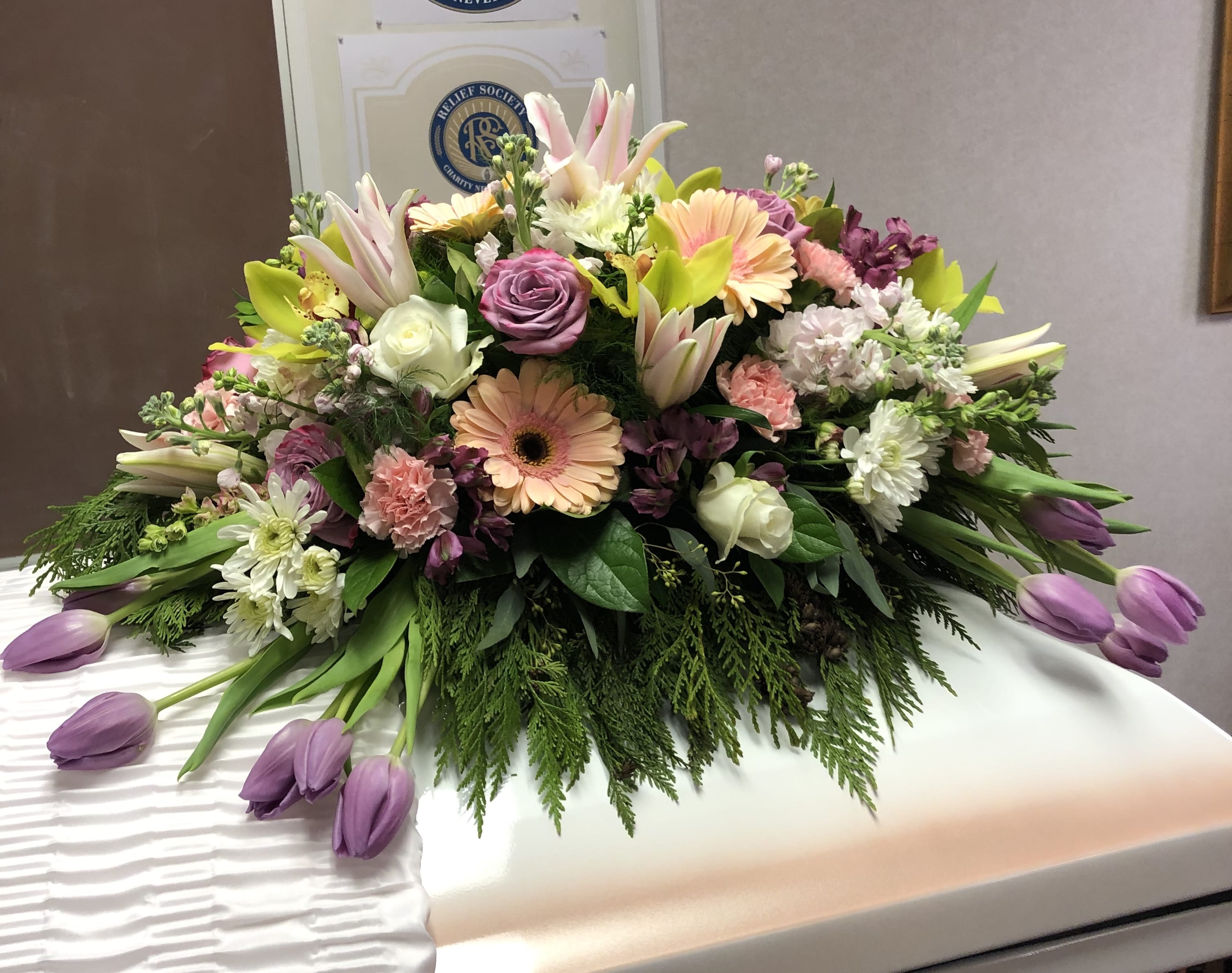 Graceful Garden Casket Spray - This graceful casket spray of bright blossoms in shades of lavender, pink, yellow and white  arranged against a backdrop of greenery, will celebrate a life well-lived.