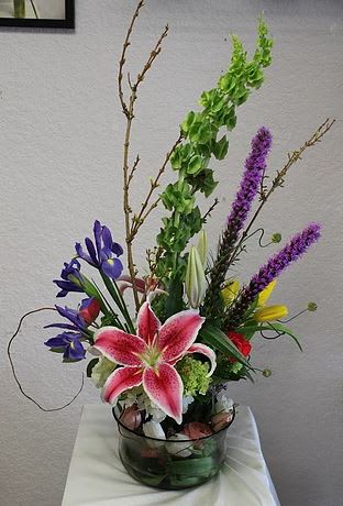 CFBD104 CFBD104 - An exquisite arrangement of Lilies, Iris, Tulips, Hydrangeas and Bells of Ireland in a specialty container.