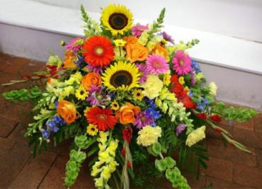 Life Celebration -  Pay colorful tribute to one whose life brought joy to many. This stunning floral arrangement, with its array of vibrant yellow and orange flowers, is truly a celebration of life.      One half-couch casket is created using vibrant orange roses and gladioli, sunflowers, purple liatris, yellow snapdragons and red gerberas.     Approximately 51&quot; W x 41&quot; H  