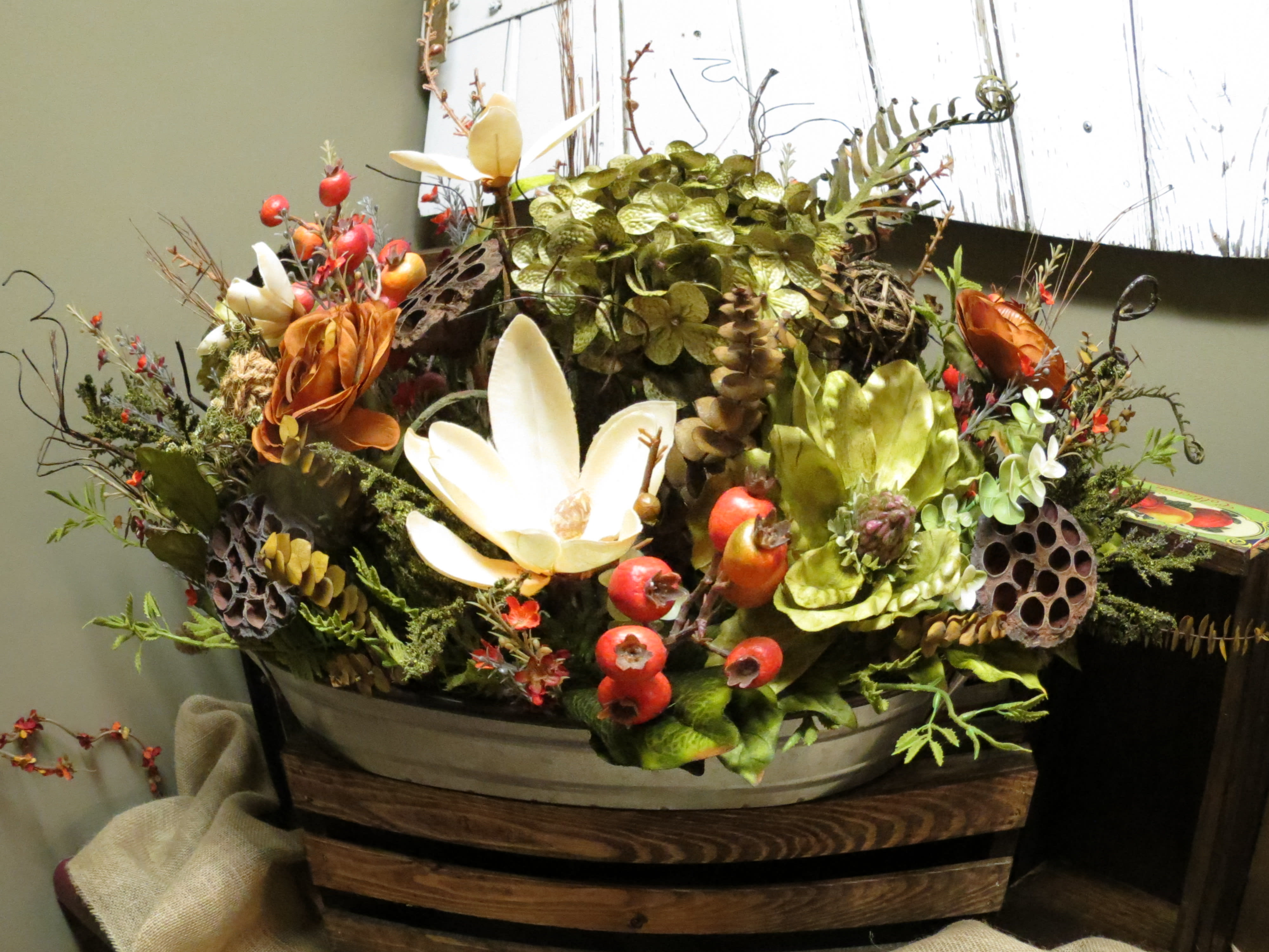 Treasured Reflections Custom Design by Cold Spring Floral Treasured Reflections Custom Design by Cold Spring Floral - Permanent Botanical Bouquet with a variety of Silk and Dried flowers such as Magnolias, Ranunculus, Berries, Seed Pods, Silk Hydrangea, and Fern in a metal and wooden plantar. Silk and Dried Flowers are subject to availability and the Container stock changes regularly.