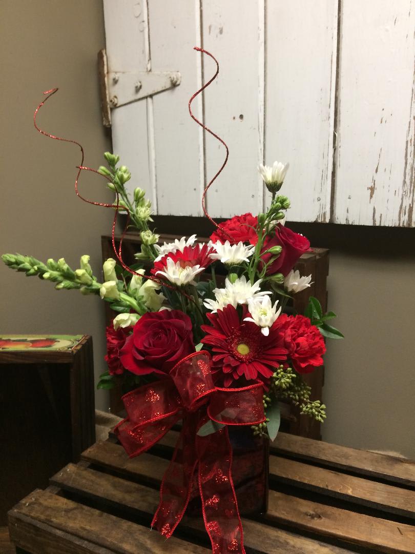 Radiance - This stunning arrangement include a red rose, red gerbera daisies, white snapdragons, white Chrysanthemums, red carnations, white larkspur and lush greens.