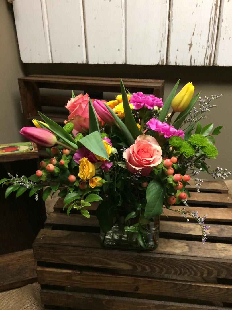 Marvellous Blooms - This arrangement includes pink roses, yellow spray roses, pink and yellow tulips, pink carnations, green button mums, hypericum berries, and lush greens.