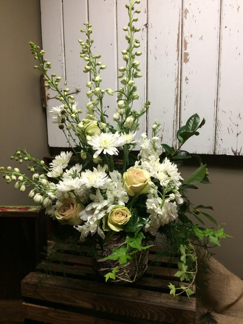 Forever Remembered - This white and cream arrangement, includes stems of roses, mums, delphinium, stock, Alstroemeria, and lush greens. 
