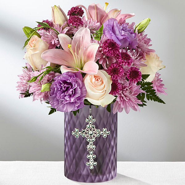The FTD God's Gifts Bouquet - A celebration of faith love and peace The FTD&reg; God's Gifts&trade; Bouquet is a special way to share in a unique moment on life's path with your recipient. Pink Asiatic Lilies and pale pink roses weave a captivating light throughout this arrangement surrounded by lavender chrysanthemums purple button poms and lavender double lisianthus. Presented in a keepsake purple glass vase accented with an ornate silver cross on the front this gorgeous bouquet creates a stunning gift they will simply never forget.