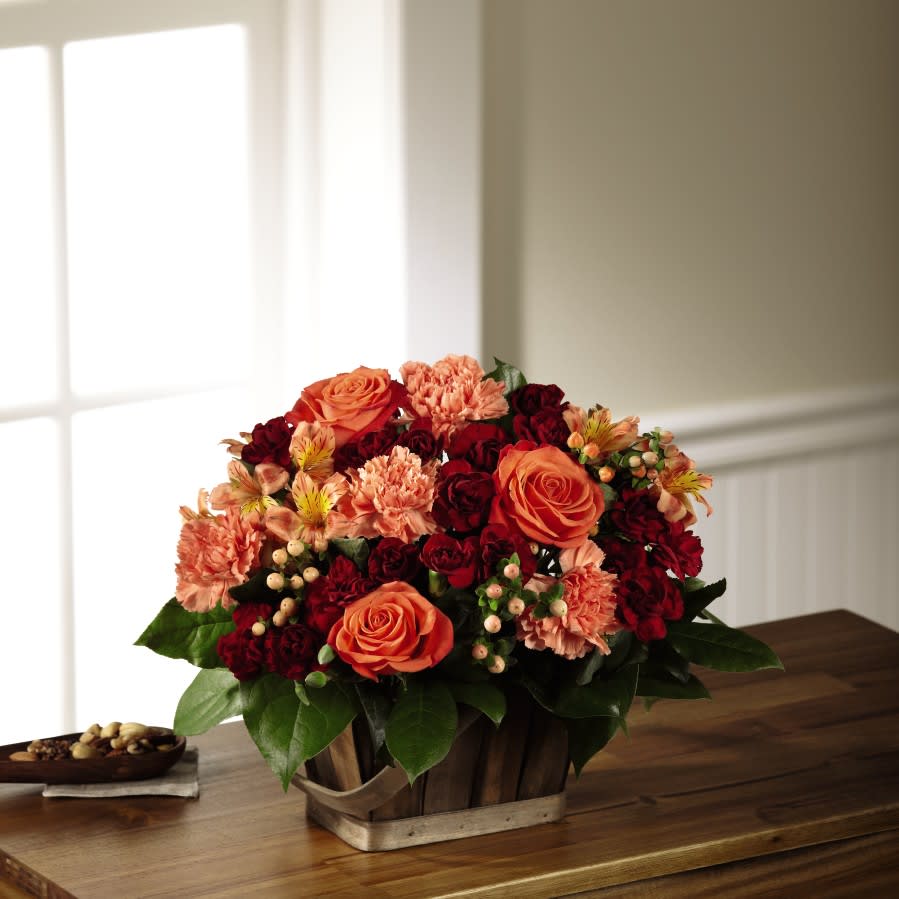 The FTD Abundant Harvest Basket The FTD Abundant Harvest Basket - Doting on fall color and harvest beauty, this fresh flower arrangement exhibits deep burgundy hues against alluring oranges to create a unique moment for your recipient. Orange roses have a truly charming look surrounded by orange carnations, orange Peruvian Lilies, and peach hypericum berries, offset by burgundy mini carnations and lush greens for an enchanting affect. Presented in a rectangular stained woodchip basket, this harvest flower arrangement is a sensational way to express your love and gratitude throughout the fall months ahead.