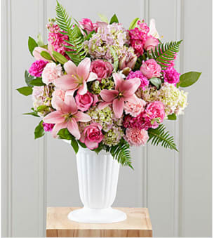 The Never-Ending Love Arrangement - This exquisite floral &quot;cloud&quot; of pink and green makes an exceptional tribute to a life lived with joy and beauty. Included in its bounty of beautiful mixed blooms are roses, hydrangea, carnations, stock and Asiatic lilies that make a painterly bouquet of pinks among lush green leaves and ferns. The arrangement, handcrafted by an artisan florist, is set in a plastic pedestal urn that replicates the look of fine porcelain. It makes a memorable and appreciated expression of sympathy for a wake, funeral service or a graveside burial ceremony. 