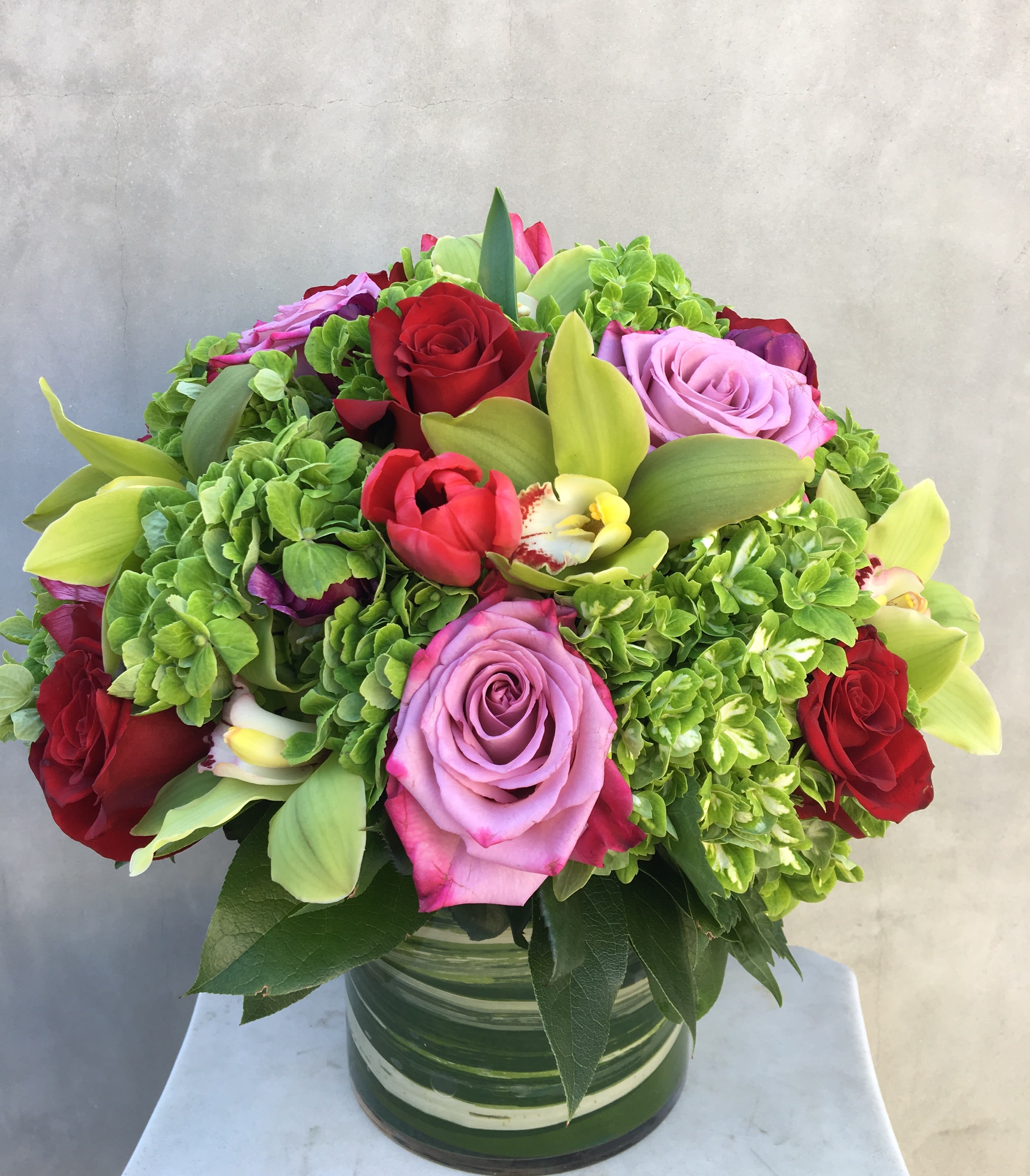 Feeling Green  - Going green enjoy a beautiful arrangement filled with green hydrangeas, roses, green orchids, and tulips in a glass vase filled with ti leaves. 