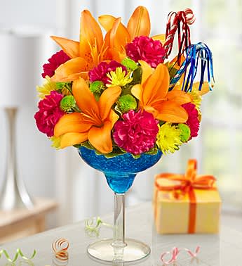It's My Birthday - Product ID: 140940  EXCLUSIVE Make every hour of their special day Happy Hour with this truly original, totally colorful birthday arrangement! Inside an oversized margarita glass, our florists hand-arrange the freshest orange lilies, hot pink carnations, green and yellow poms, then add a pair of party horns to get the celebration started with a smile! Cocktail-shaped floral arrangement of orange lilies, hot pink carnations, green button poms, yellow cushion poms and variegated pittosporum, topped with a pair of birthday horns Artistically designed in a 10&quot;H reusable acrylic margarita glass filled with blue crystal accents Extra Large arrangement measures approximately 14&quot;H x 9&quot;L Large arrangement measures approximately 13&quot;H x 8.5&quot;L Medium arrangement measures approximately 12&quot;H x 8&quot;L Small arrangement does not include birthday blowers and measures approximately 12&quot;H x 7&quot;L Our florists select the freshest flowers available so colors and varieties may vary Lilies may arrive in bud form and will open to full beauty over the next 2-3 days