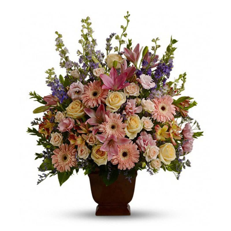  Teleflora's Loving Grace - A warm and peaceful bounty of pastel blossoms gently expresses love and respect. A gracefully composed arrangement appropriate for home or service.  Fresh flowers such as peach and light pink roses, lavender and purple larkspur, pink asiatic lilies, alstroemeria, gerberas and lisianthus are set in an exclusive Noble Heritage urn.      Orientation: One-Sided      All prices in USD ($)      Standard      T220-1A 