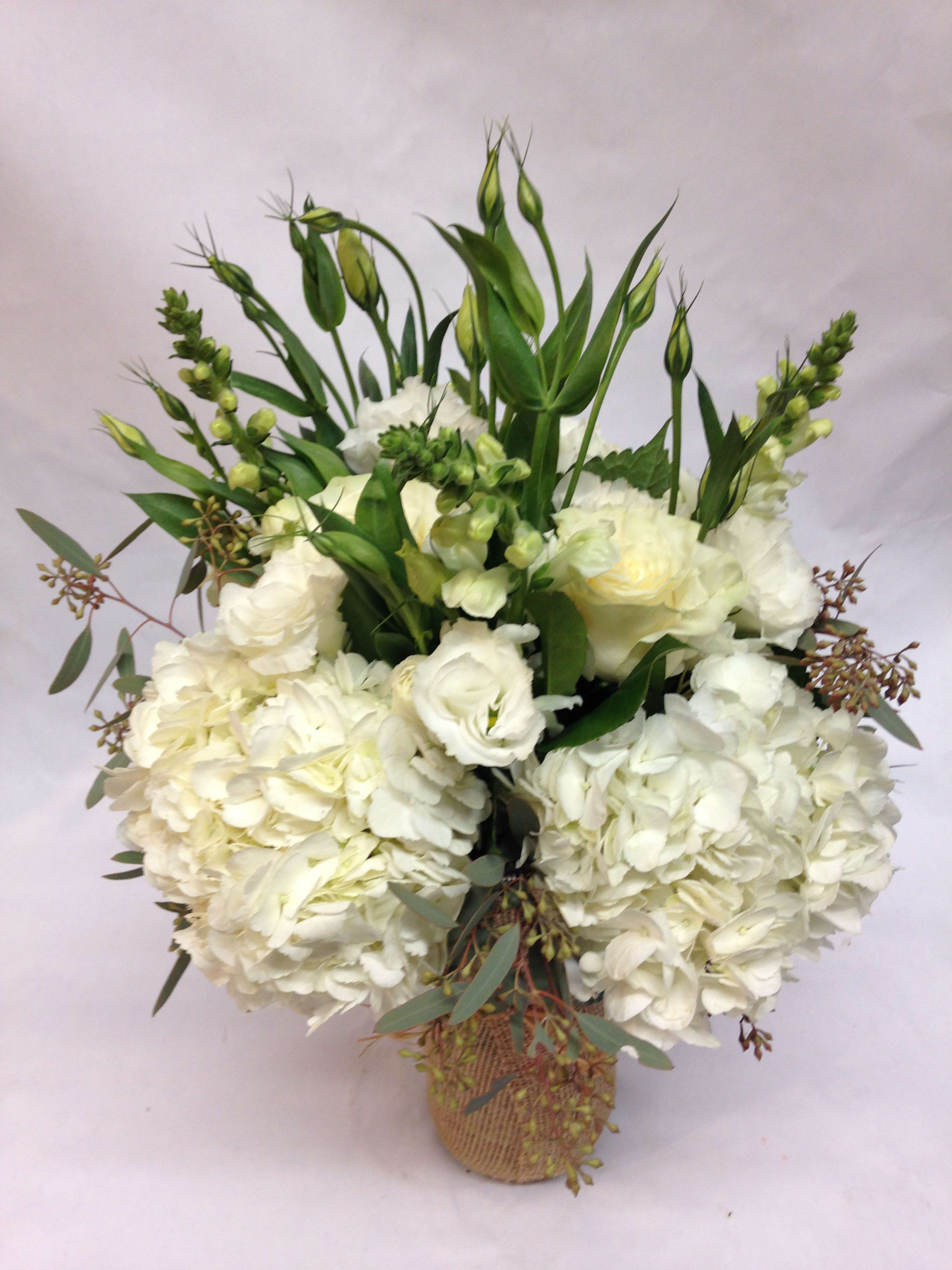 Frosty Delight - This burlap-wrapped vase arrangement has lots of character with a modern white look. It features white hydrangea, roses, snapdragon, and eucalyptus for a crisp mix of green and white. Featured Arrangement: $175.00 (Regular Price)
