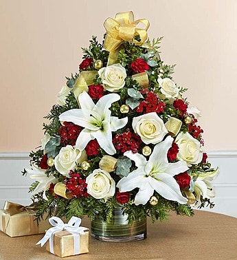 Christmas Flower Tree Christmas Flower Tree - Luxurious fresh-cut Christmas tree! Standing a full two feet tall, this holiday highlight is hand-designed with xmas greens, roses, lilies, carnations, dianthus and much more in hues of cream and burgundy. Decorative gold balls and ribbon complete the elegant arrangement guaranteed to awe your guests... Providing all materials are available, substitution of flowers and greens can occur