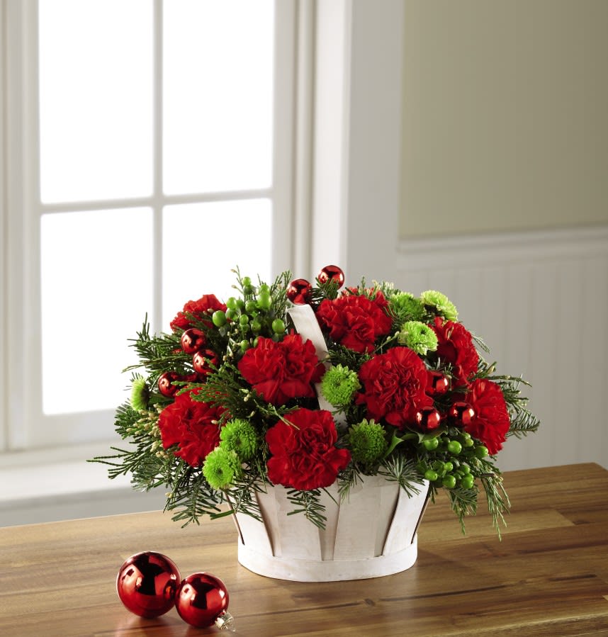 The FTD Winter Wishes Basket The FTD Winter Wishes Basket - Taking traditional Christmas colors and turning up the volume to create a bright and brilliant arrangement, this fresh flower bouquet is ready to bring holiday joy to even the darkest corner of your recipient's home. Rich red roses and red carnations are accented with green hypericum berries, green button poms, clusters of shining red glass holiday balls, and an assortment of fragrant Christmas greens. Arranged to perfection in a white wash woodchip basket, this gift of flowers is ready to make a splash as a centerpiece, or when placed on the buffet table or side counter for their holiday gathering.