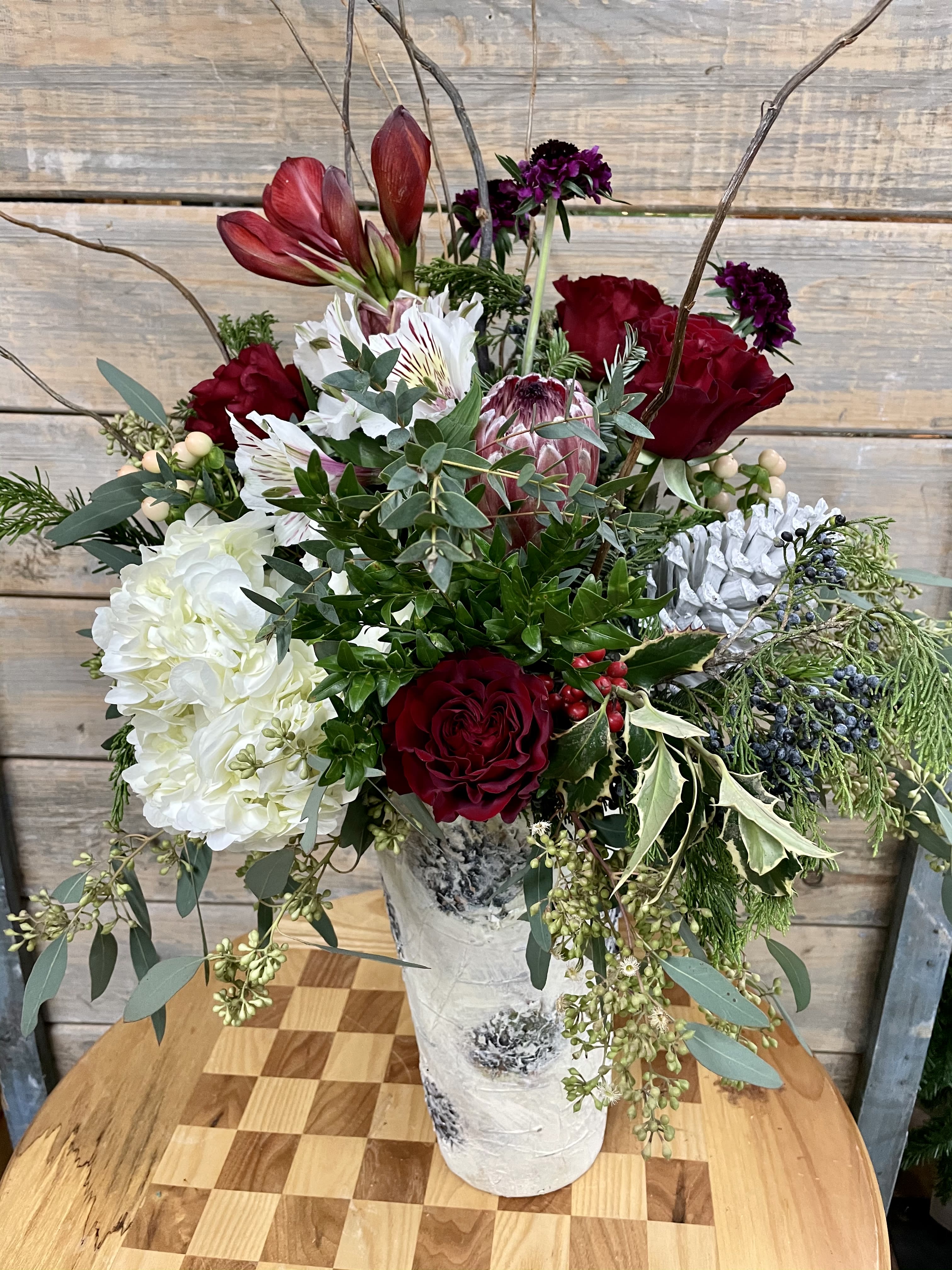 Joy of Christmas - A tall classic red and white Christmas arrangement with a selection of classic flowers and tropical proteas.