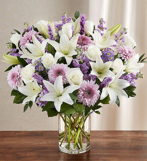 Lavender & White Sincerest Sorrow Lavender & White Sincerest Sorrow - Our lush, bountiful bouquet of lavender and white blooms features an elegant mix of roses, lilies and cremones, hand-designed inside a classic clear glass vase.