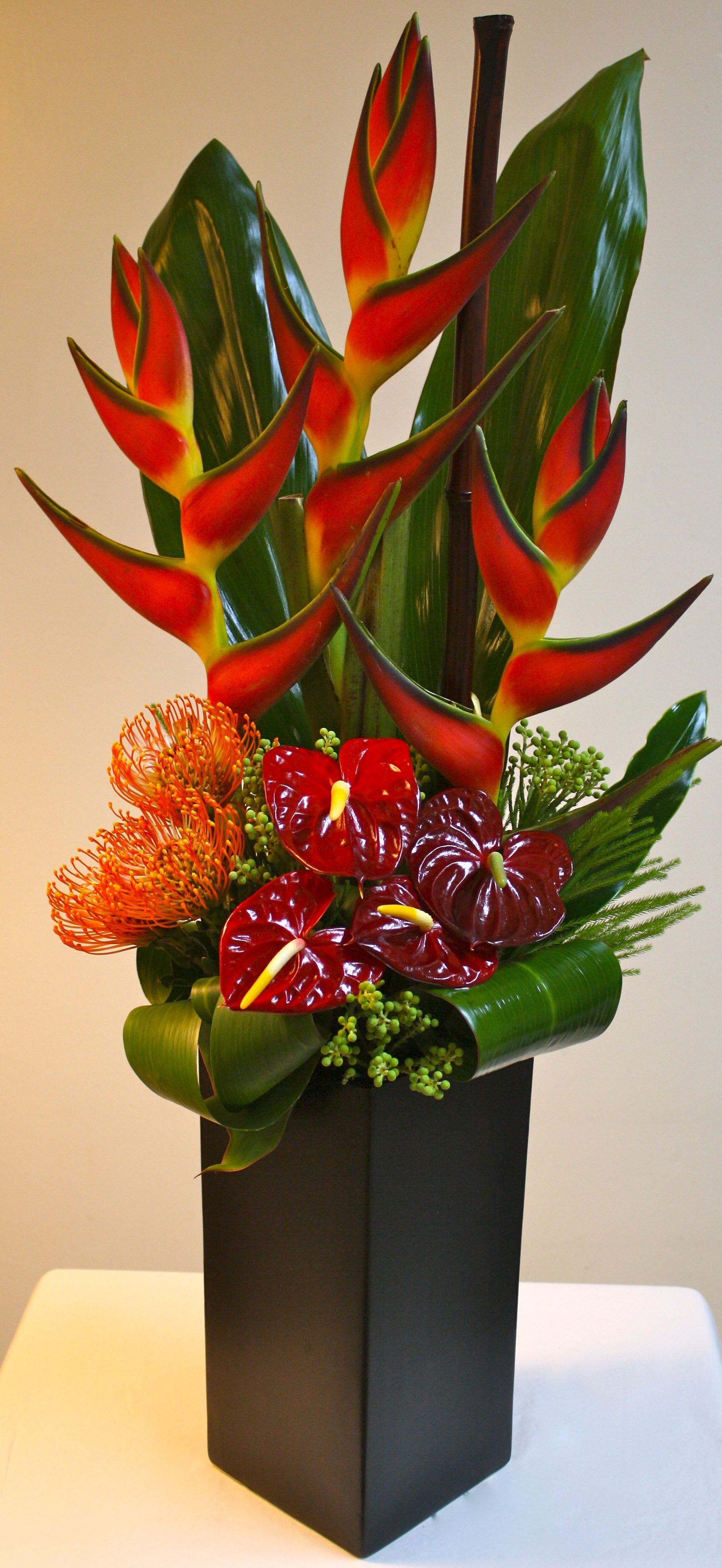 Tropical Island Tropical Island - Escape to tropical Island with this stunning, sculptural presentation. tropical ti leaves and eye-catching Heliconia mixed with mosquito portea and red anthuriums