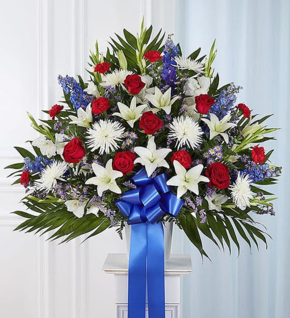 Sympathy Basket: Red, White, &amp; Blue - The love they showed for their country is as deep as the love felt by those mourning their loss. Meticulously crafted by our expert florists to honor a proud veteran who has passed away, our majestic standing basket arrangement is filled with lush blooms in patriotic red, white and blue, creating a fitting final tribute for the funeral services.