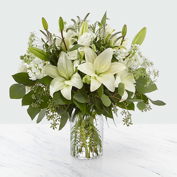 Alluring Elegance Bouquet - Our Alluring Elegance Bouquet is a striking array of ivory and green within a clear textured glass vase. Handcrafted using Asiatic lilies interwoven with white Veronica white stock Queen Anne’s lace silver dollar eucalyptus and seeded eucalyptus this bouquet graces every room with a touch of elegance. GOOD bouquet is approx. 17&quot;H x 14&quot;W. BETTER bouquet is approx. 18&quot;H x 17&quot;W. BEST bouquet is approx. 19&quot;H x 18&quot;W.