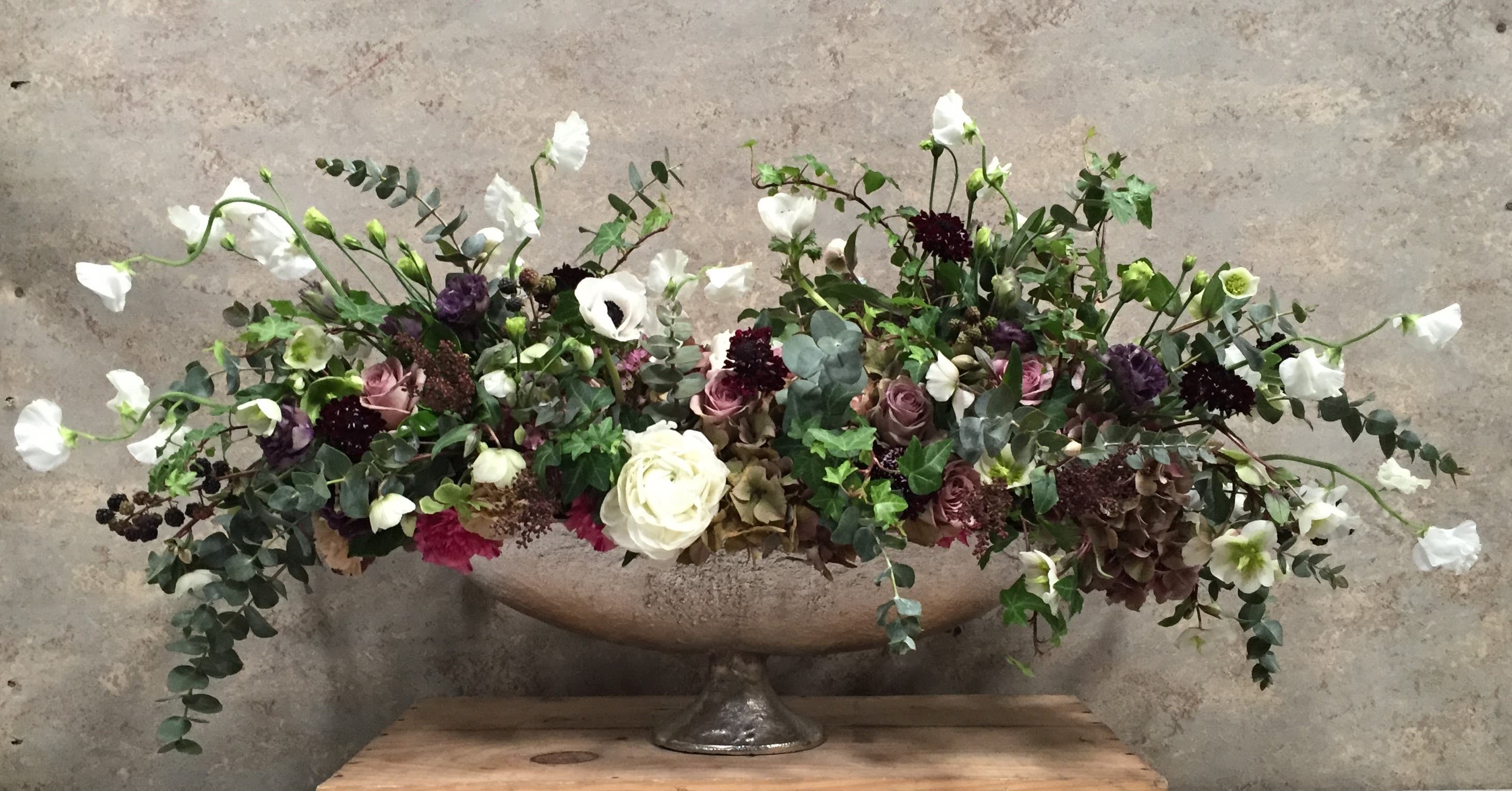 Flowers for the Artiste. Flowers for the Artiste. - Oblong metal pedestal brimming with romance. Tradition meets whimsy in this seasonally abundant arrangement. Contrasting colors from brooding dark hues to light incorporating seasonal greens and garden roses, ranunculas, sweet peas and ranunculas.