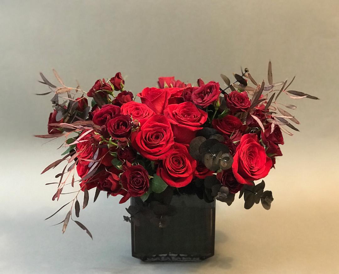 Midnight Shades - Smoke glass vase with abundant blooms of reds and burgundy roses