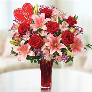 Key to my heart - This gorgeous arrangement features red roses and pink lilies surrounded by pink and green floral accents, all in a sleek, sophisticated red glass vase with a clear bottom. Included is a keepsake keychain designed exclusively by artist Sandra Magsamen