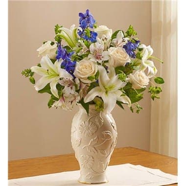 Loving Blooms in Lenox - Blue & White - Designed inside our exclusive Lenox® vase, this soothing, elegant bouquet will help you offer comfort and support during a difficult time. We arrange blue delphinium, white roses, lilies and more inside this exquisite Lenox® porcelain vase, featuring a raised, stylized floral design and a 24 karat gold trim at the base. Both classic and beautiful, this one-of-a-kind gift helps convey your deepest sympathies to those who have lost a loved one. 145620