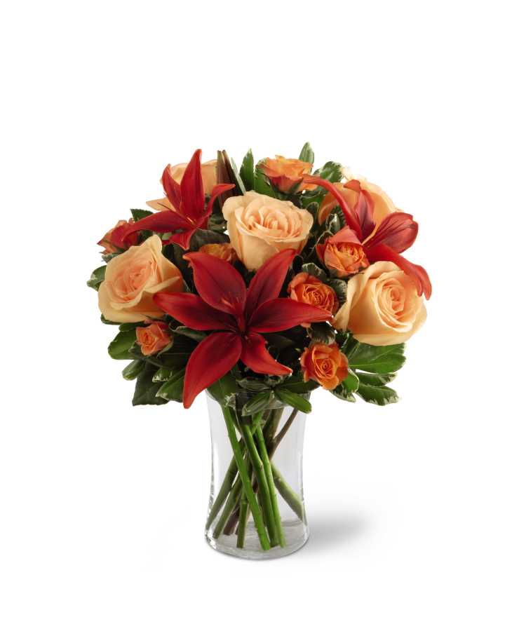 The FTD Warmth &amp; Comfort Bouquet - The FTD Warmth &amp; Comfort Bouquet is a colorful sentiment that gorgeously conveys your deepest sympathies for their loss. Sweet peach roses mingle with rusted red Asiatic lilies, orange spray roses and lush greens, elegantly arranged in a clear glass vase, to create a warm display of captivating color that offers comfort with each graceful bloom.